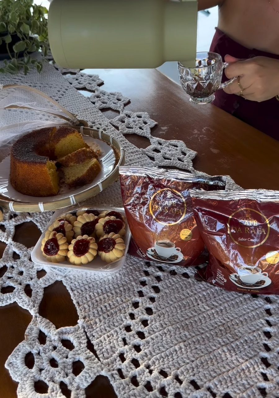 Mesa de café da tarde com bolo, biscoitos e pacotes do Café da Rafa
